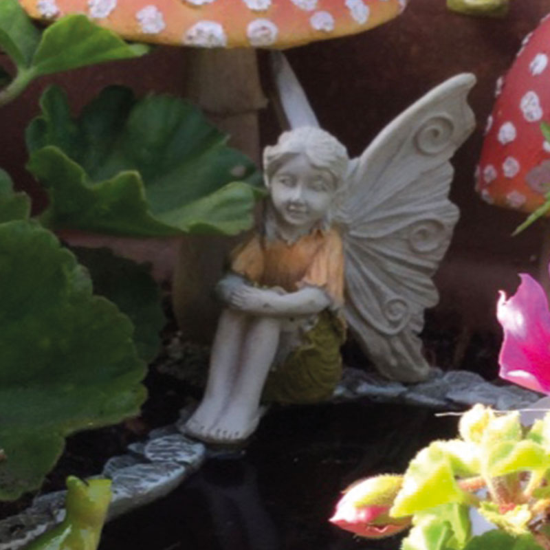 Fiddlehead Fairy Garden Fairy with hands around knees 